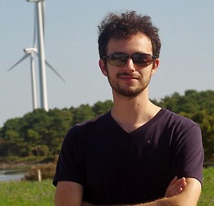Elliot Simon standing in front of a lake with windmills in the background